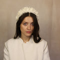 A woman wearing a white cream-padded headband with fabric flowers. Cream padded headband with fabric flowers, handmade by SJL Couture
