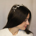 A woman wearing a silver diamante and pearl headpiece on her head. Silver diamanté and pearl bridal headpiece
