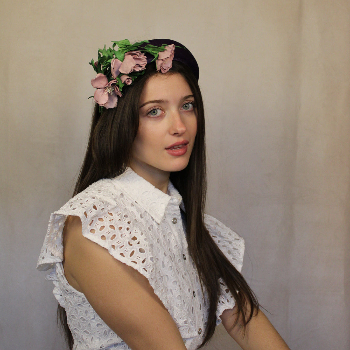 A person wearing a headband with pink and green floral design and lamb's leather roses. Velour headband with hand-sewn lamb's leather roses