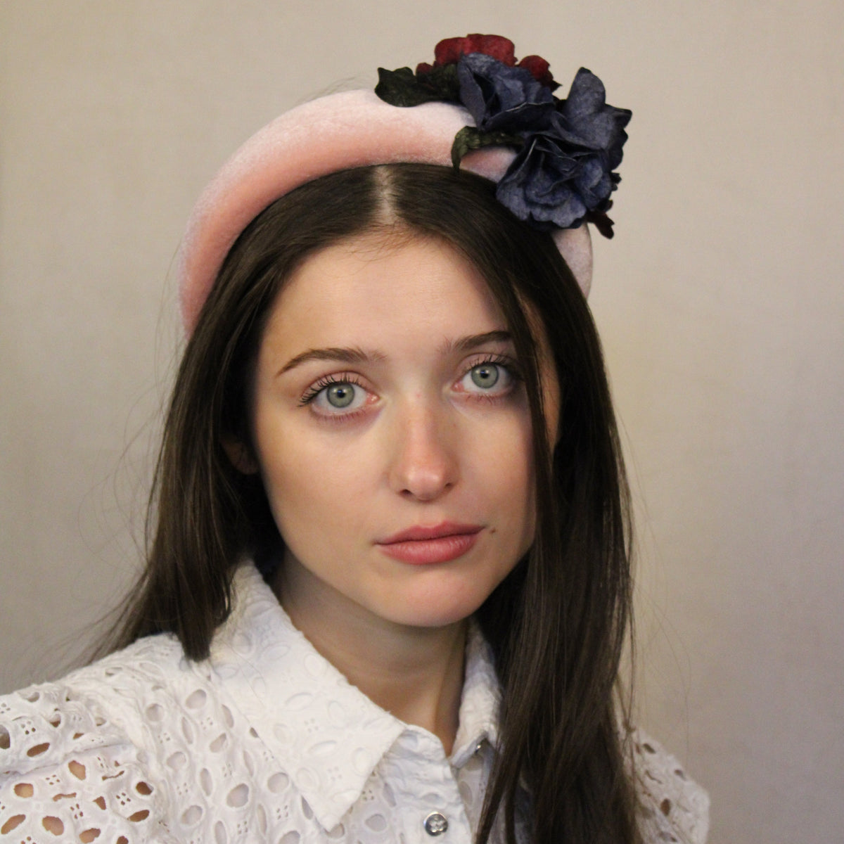 A woman wearing a hand-made pink and navy padded headband with sustainable fish leather flowers sewn to pale pink velvet. Pink and navy padded headband with fish leather flowers on pale pink velvet