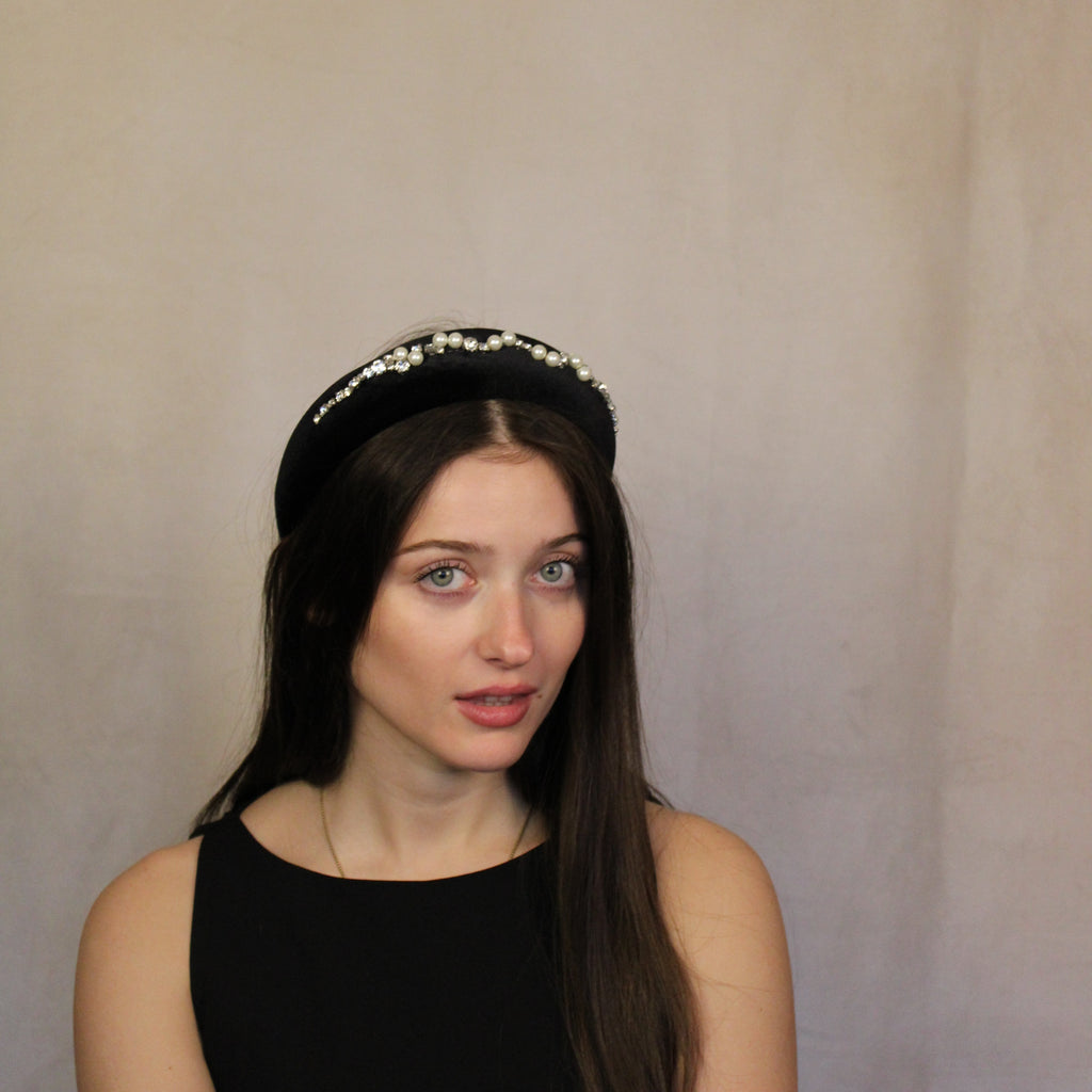 A woman wearing a black velour headband with diamanté embellishments.
