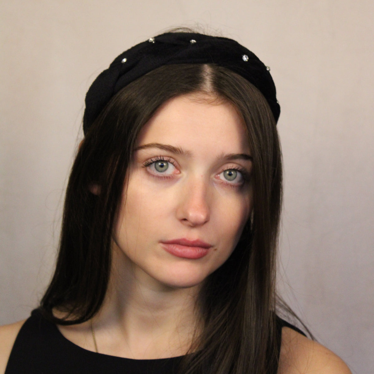 A person wearing a black velour headband with small diamantés. Black velour headband with small diamantés