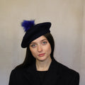 A woman wearing a navy blue wool beret with an indigo pompom. Navy blue wool beret with indigo pompom