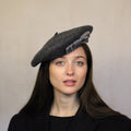 A woman wearing a gray wool beret with a velvet bow trim. Grey wool beret with velvet bow trim